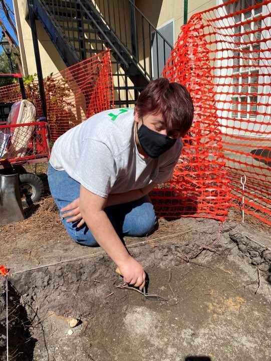 A student carefully works at the excavation