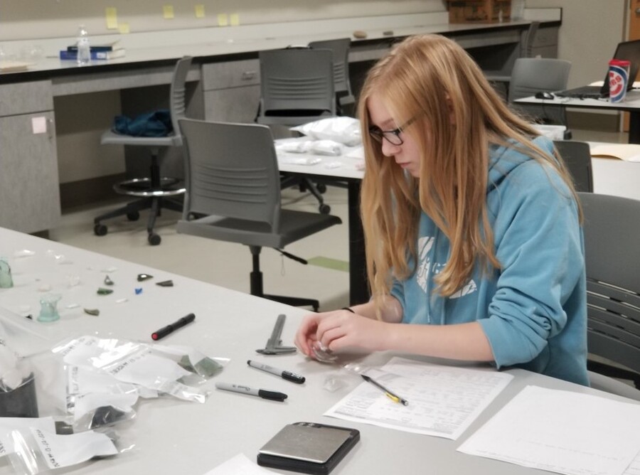A student studies artifacts found at the excavation site